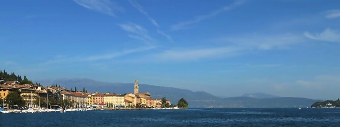 Trip Litauen beliebte Urlaubsziele am Gardasee -  Mit einer Fläche von 370 km² ist der Gardasee der größte See Italiens. Es liegt am Fuße der Alpen und erstreckt sich über drei Staaten: Lombardei, Venetien und Trentino. Die maximale Tiefe des Sees beträgt 346 m, er hat eine längliche Form und sein nördliches Ende ist sehr schmal. Dort ist der See von den Bergen der Gruppo di Baldo umgeben. Du trittst aus deinem gemütlichen Hotelzimmer und es begrüßt dich die warme italienische Sonne. Du blickst auf den atemberaubenden Gardasee, der in zahlreichen Blautönen schimmert - von tiefem Dunkelblau bis zu funkelndem Türkis. Majestätische Berge umgeben dich, während die Brise sanft deine Haut streichelt und der Duft von blühenden Zitronenbäumen deine Nase kitzelt. Du schlenderst die malerischen, engen Gassen entlang, vorbei an farbenfrohen, blumengeschmückten Häusern. Vereinzelt unterbricht das fröhliche Lachen der Einheimischen die friedvolle Stille. Du fühlst dich wie in einem Traum, der nicht enden will. Jeder Schritt führt dich zu neuen Entdeckungen und Abenteuern. Du probierst die köstliche italienische Küche mit ihren frischen Zutaten und verführerischen Aromen. Die Sonne geht langsam unter und taucht den Himmel in ein leuchtendes Orange-rot - ein spektakulärer Anblick.